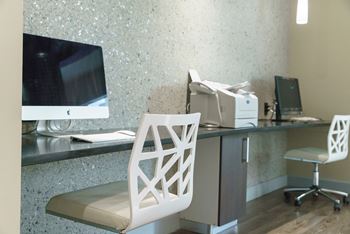 a desk with a computer and a chair in a hotel room